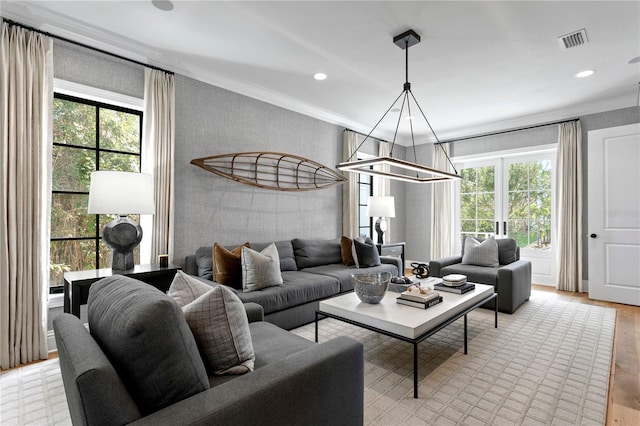 living room featuring light hardwood / wood-style floors, a wealth of natural light, and crown molding