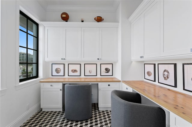 home office with built in desk and ornamental molding