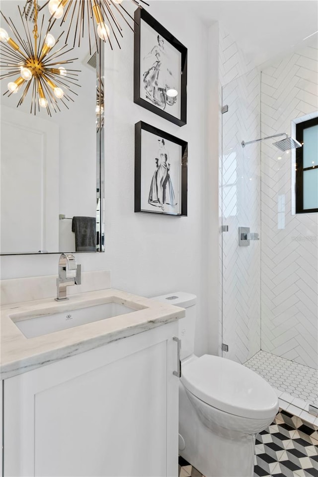 bathroom featuring tiled shower, toilet, vanity, and a notable chandelier