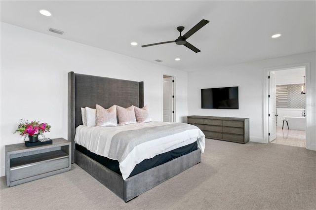 bedroom with ceiling fan, light colored carpet, and ensuite bathroom