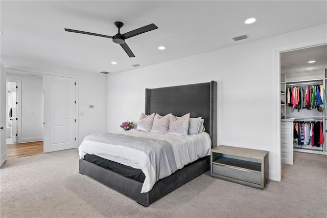 carpeted bedroom with ceiling fan, a walk in closet, and a closet