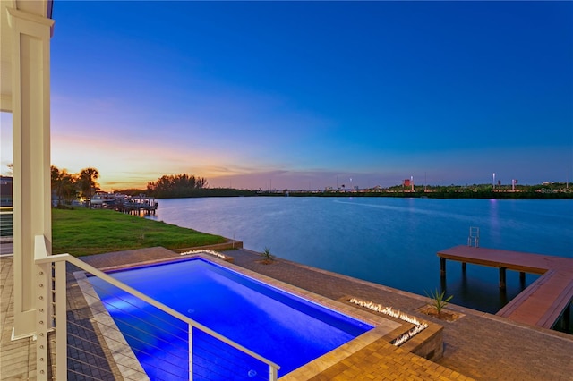 pool at dusk featuring a water view