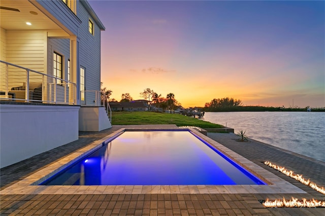 pool at dusk featuring a water view