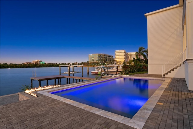 pool at dusk featuring a boat dock and a water view