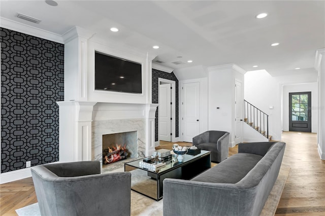 living room with a premium fireplace, light wood-type flooring, and ornamental molding