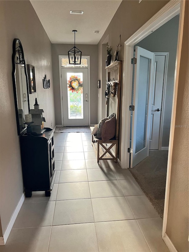 entryway featuring light tile patterned floors and a notable chandelier