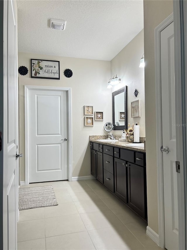 bathroom featuring tile patterned flooring, vanity, and a textured ceiling