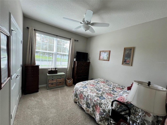 bedroom featuring ceiling fan, light colored carpet, and a textured ceiling