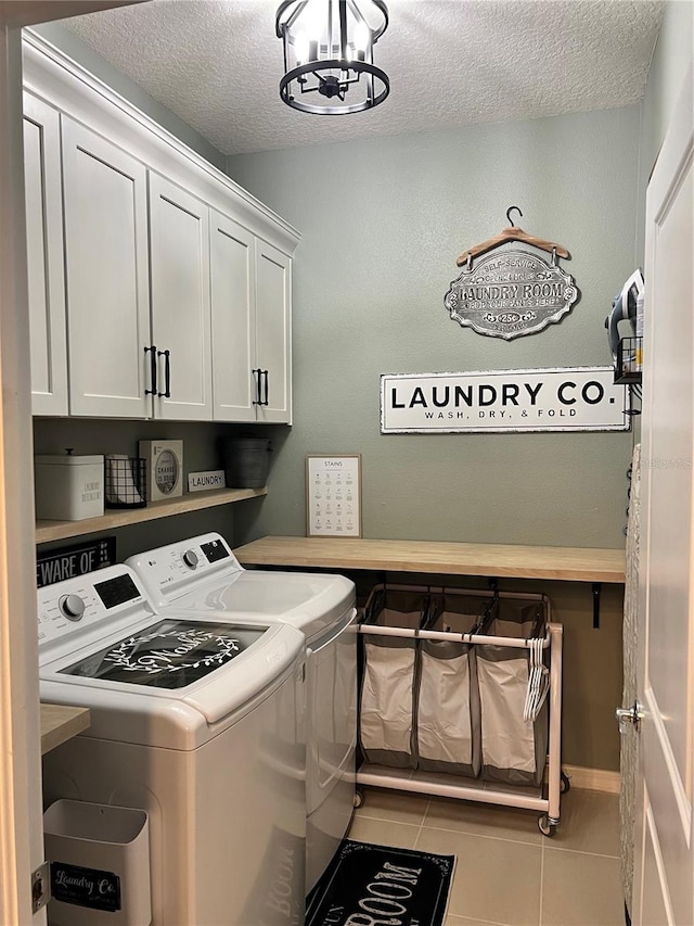 clothes washing area with light tile patterned floors, cabinets, a textured ceiling, and independent washer and dryer