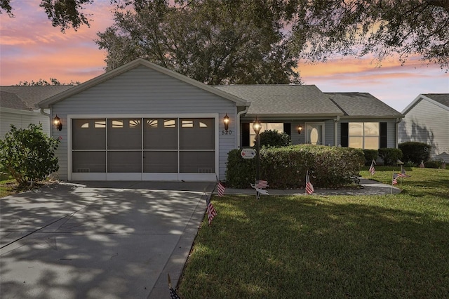 ranch-style home featuring a garage and a yard