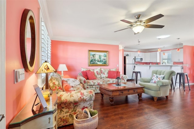 living room with ceiling fan, ornamental molding, and dark wood-type flooring