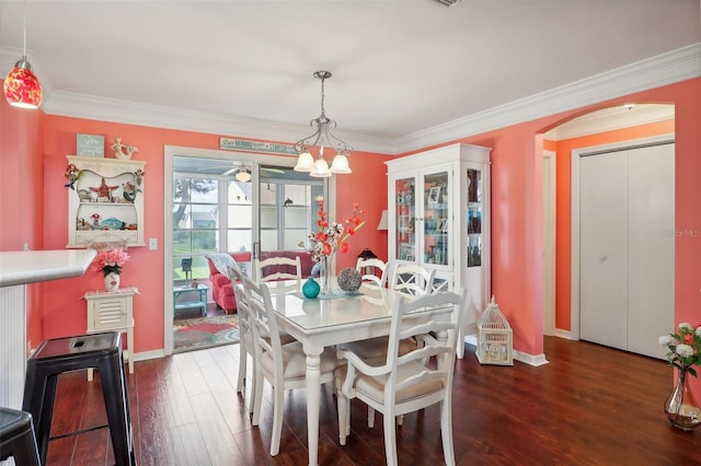 dining space featuring dark hardwood / wood-style flooring, an inviting chandelier, and crown molding