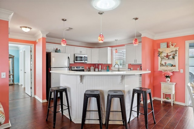 kitchen with a breakfast bar area, white cabinetry, hanging light fixtures, and dark hardwood / wood-style floors