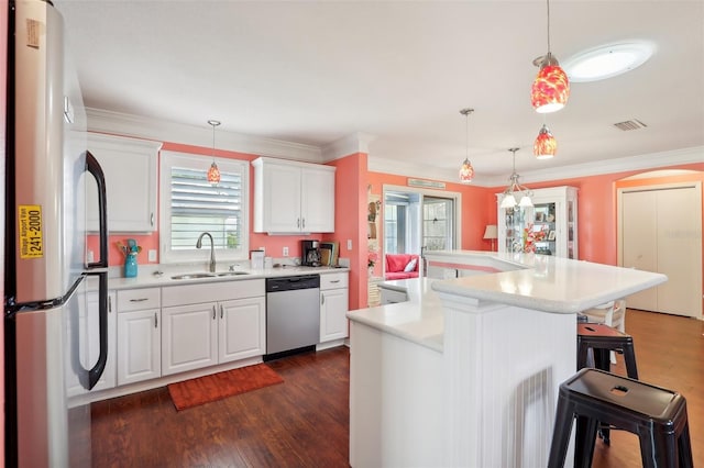 kitchen featuring appliances with stainless steel finishes, a breakfast bar, sink, pendant lighting, and white cabinetry