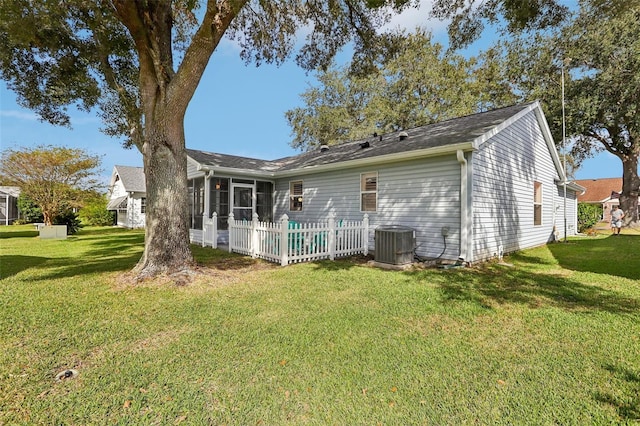 back of property featuring a sunroom, central AC unit, and a lawn