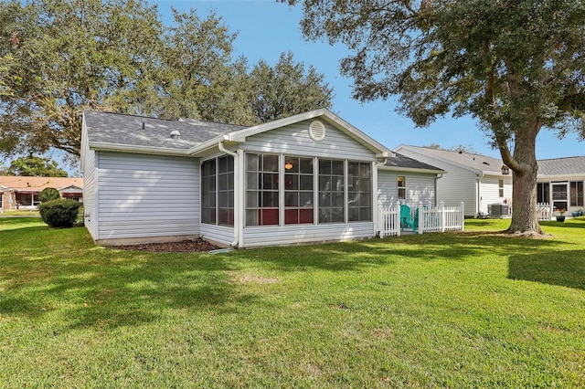 rear view of house featuring central air condition unit, a sunroom, and a yard