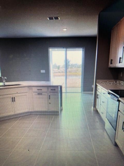 kitchen featuring light tile patterned floors, white cabinetry, sink, and stainless steel range