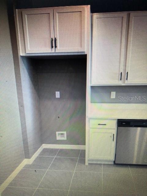 kitchen featuring stainless steel dishwasher, white cabinets, and light tile patterned floors