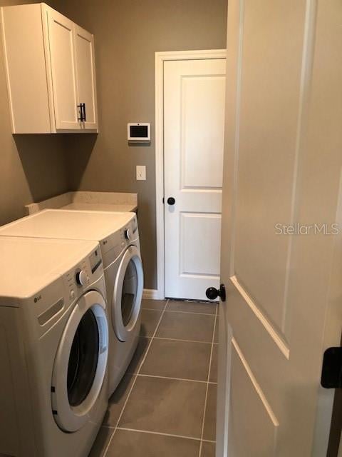 washroom featuring cabinets, independent washer and dryer, and dark tile patterned flooring