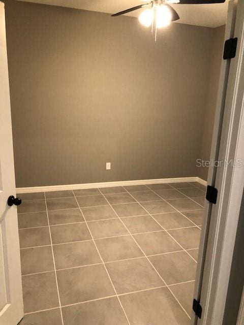 tiled spare room with ceiling fan