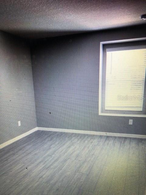 unfurnished room with hardwood / wood-style flooring and a textured ceiling