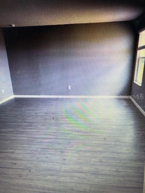 unfurnished room with dark wood-type flooring