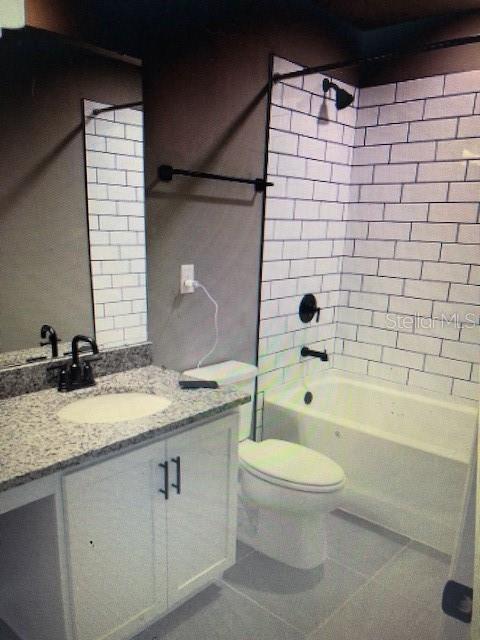 full bathroom with tiled shower / bath combo, vanity, tile patterned floors, and toilet