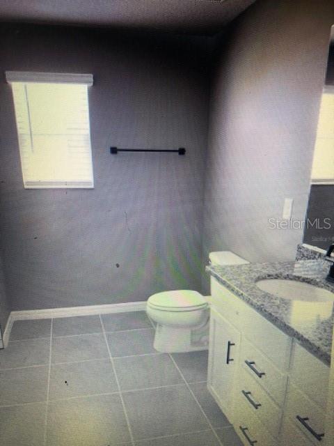 bathroom featuring vanity, tile patterned floors, and toilet