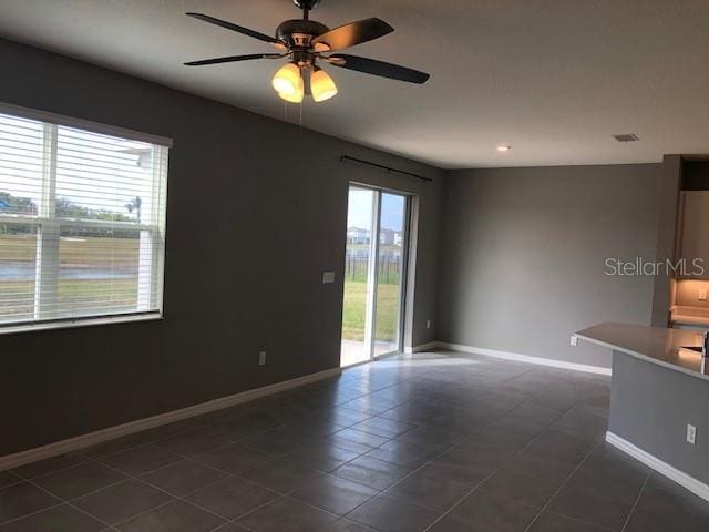 tiled empty room featuring ceiling fan