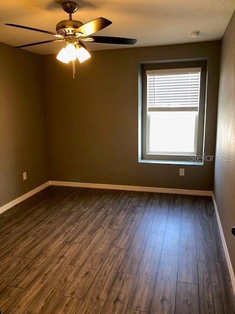 empty room featuring ceiling fan and dark hardwood / wood-style flooring