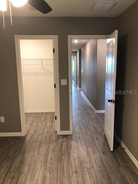 unfurnished bedroom with ceiling fan, wood-type flooring, and a spacious closet