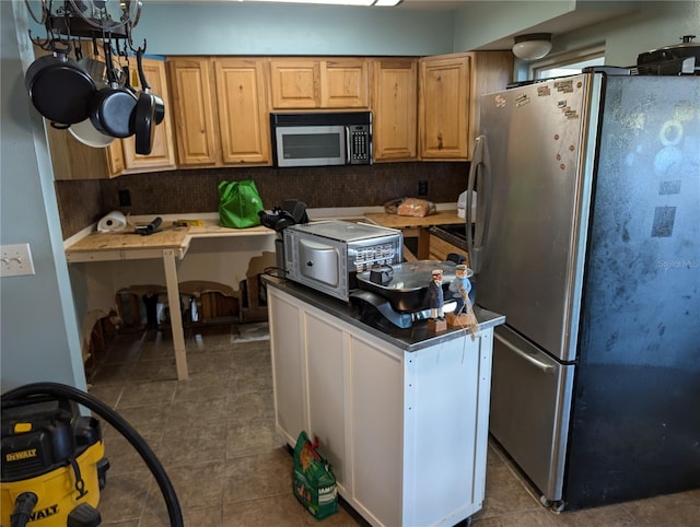 kitchen featuring decorative backsplash, dark tile patterned flooring, and appliances with stainless steel finishes