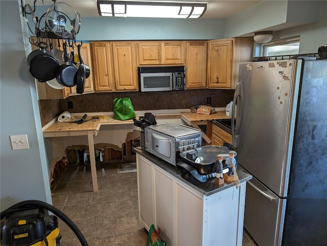 kitchen featuring backsplash, dark tile patterned floors, and stainless steel appliances