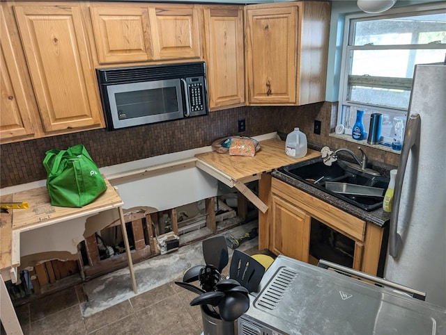 kitchen featuring decorative backsplash, dark tile patterned floors, sink, and appliances with stainless steel finishes