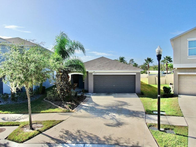 view of front facade featuring driveway, roof with shingles, an attached garage, a front lawn, and stucco siding