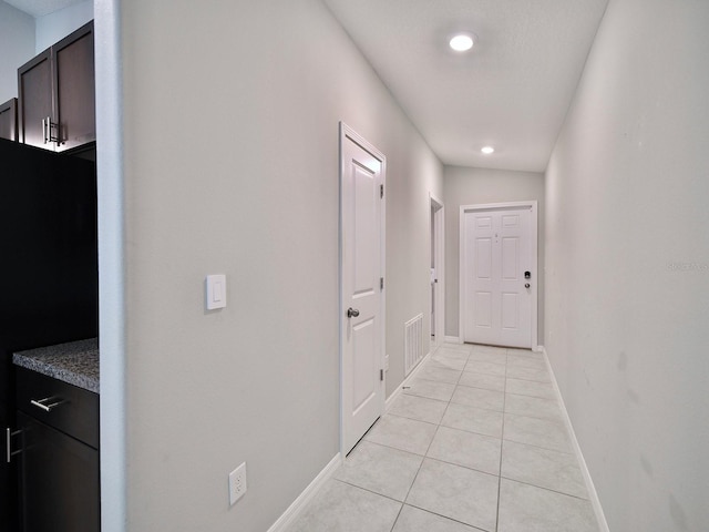 hall with baseboards, visible vents, and light tile patterned flooring