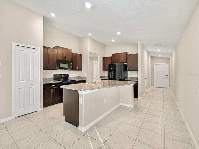 kitchen featuring black appliances, dark brown cabinets, light tile patterned flooring, and a center island with sink