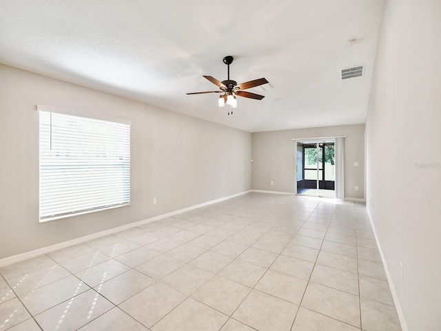 spare room with baseboards, light tile patterned floors, visible vents, and a ceiling fan