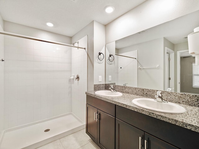 bathroom featuring double vanity, tiled shower, a sink, and tile patterned floors