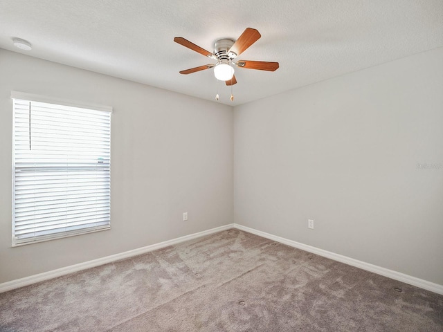 spare room featuring carpet floors, ceiling fan, a textured ceiling, and baseboards