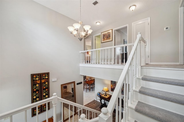 stairway with visible vents, a notable chandelier, and a towering ceiling