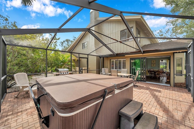 view of patio with glass enclosure and a hot tub