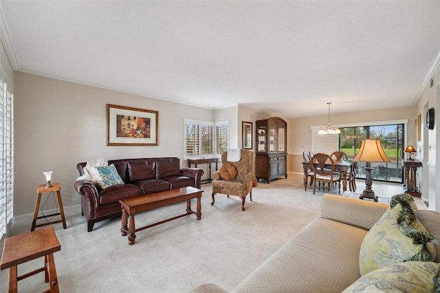 living area with baseboards, a chandelier, light colored carpet, and ornamental molding