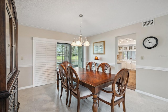 dining space with visible vents, an inviting chandelier, ornamental molding, a textured ceiling, and baseboards