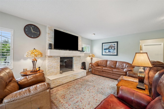 living area with a fireplace, a textured ceiling, and wood finished floors