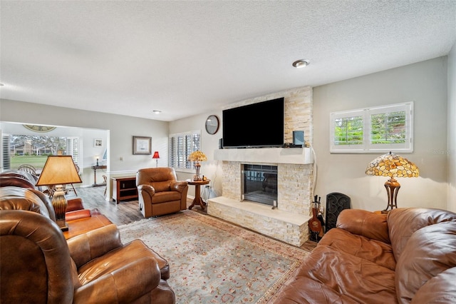 living room featuring a fireplace, a textured ceiling, and wood finished floors