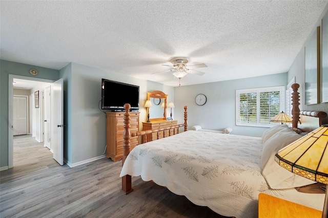 bedroom with a ceiling fan, light wood-style flooring, baseboards, and a textured ceiling