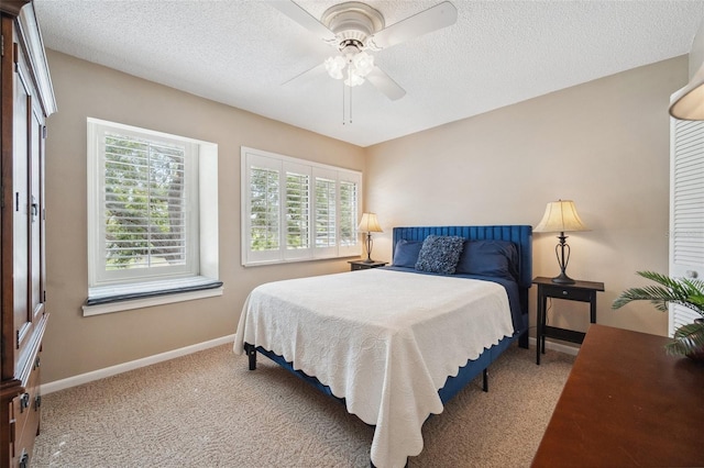 carpeted bedroom featuring ceiling fan, a textured ceiling, and baseboards