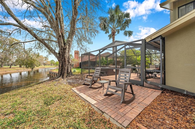 view of yard featuring a patio area, a water view, a lanai, and a hot tub