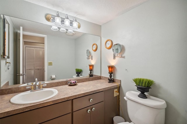 half bathroom with toilet, a textured ceiling, and vanity